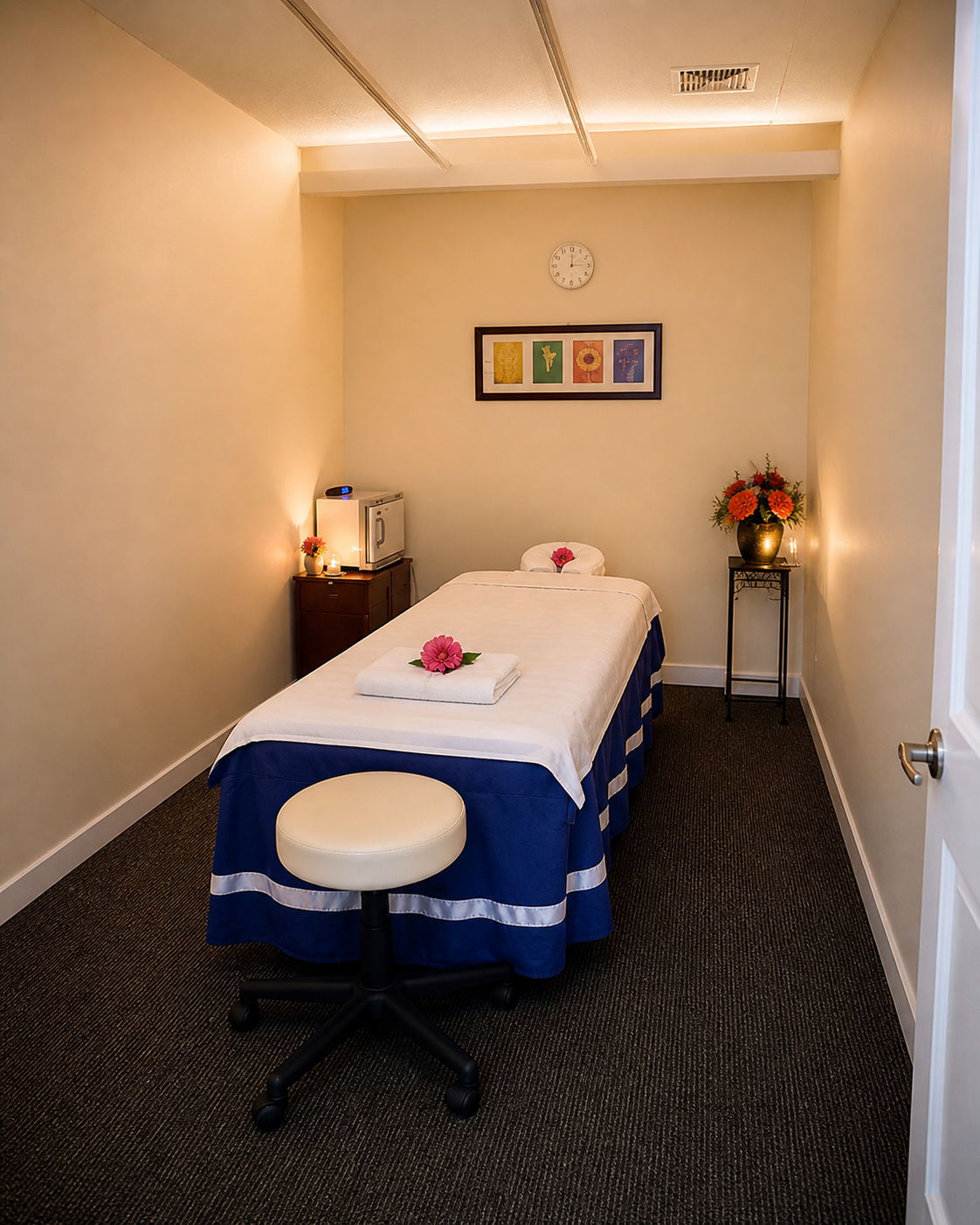 A softly-lit Moon Spa treatment room with a draped bed, candle, and small botanical art